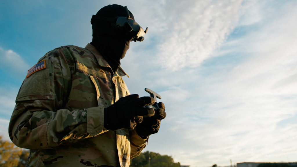 Man operating drone in camouflage gear.